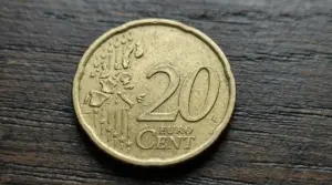 Moneta da 20 centesimi di euro con evidente errore di conio su sfondo in legno