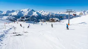 Sciatori su una pista innevata con impianti di risalita e montagne sullo sfondo