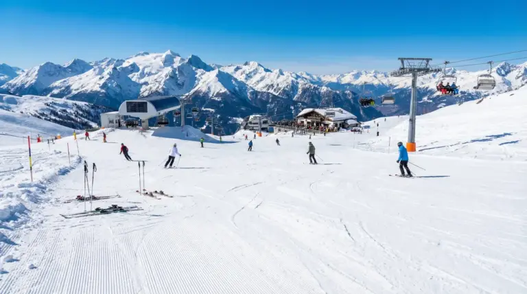 Sciatori su una pista innevata con impianti di risalita e montagne sullo sfondo