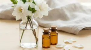 Fiori bianchi in un vaso di vetro con due boccette di olio essenziale su un tavolo