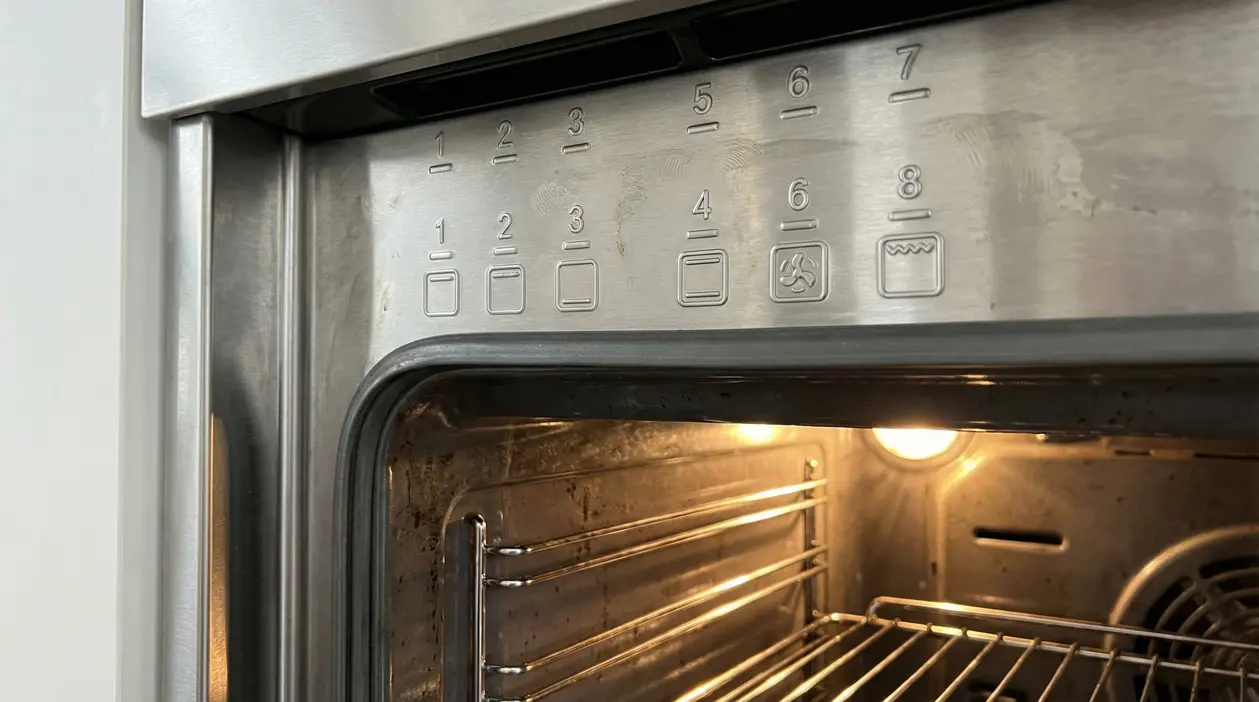 Primo piano del pannello interno di un forno con numeri e simboli incisi sul metallo